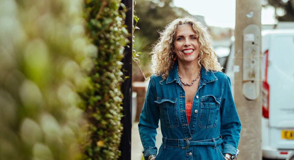 Anna Balcombe with curly blonde hair, smiling outdoors