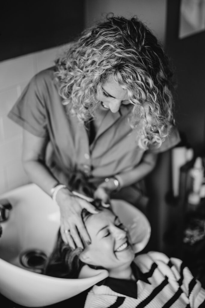Anna Balcombe washing a smiling client's hair at the salon basin